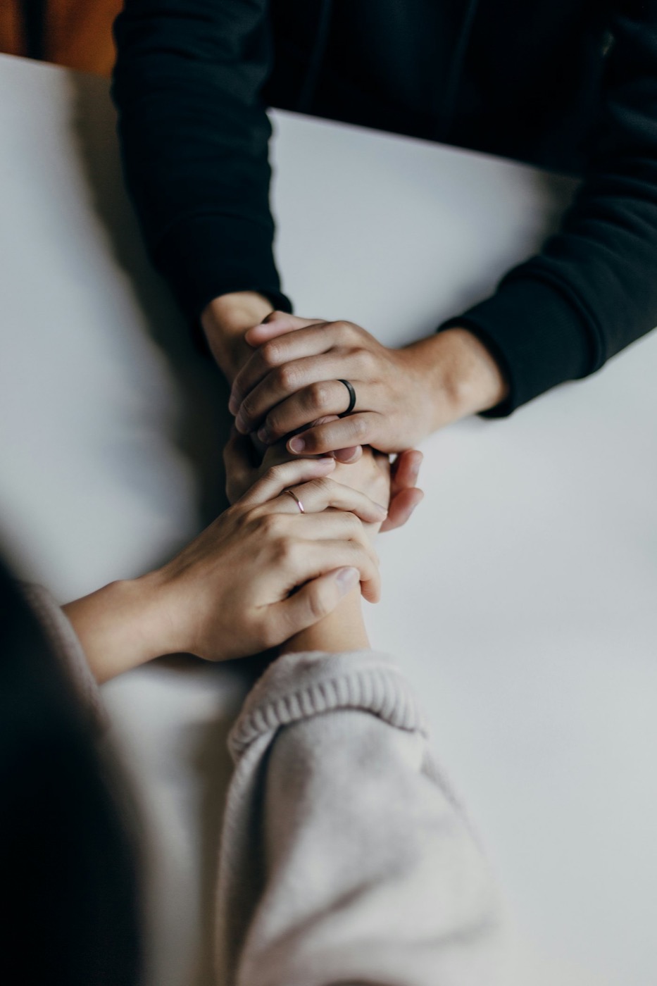Two people holding hands across a table in a moment of reassurance.