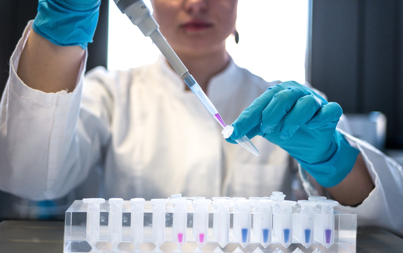 A researcher pipetting samples into tubes in a laboratory.