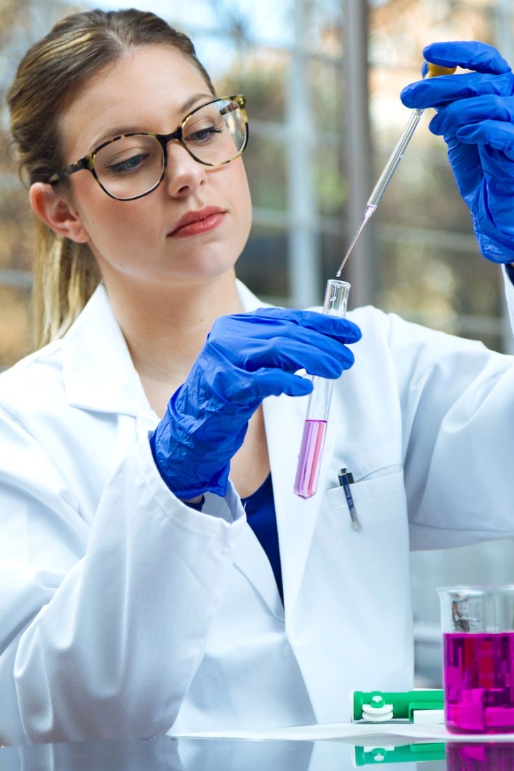 A researcher in a lab coat pipetting a sample into a test tube.